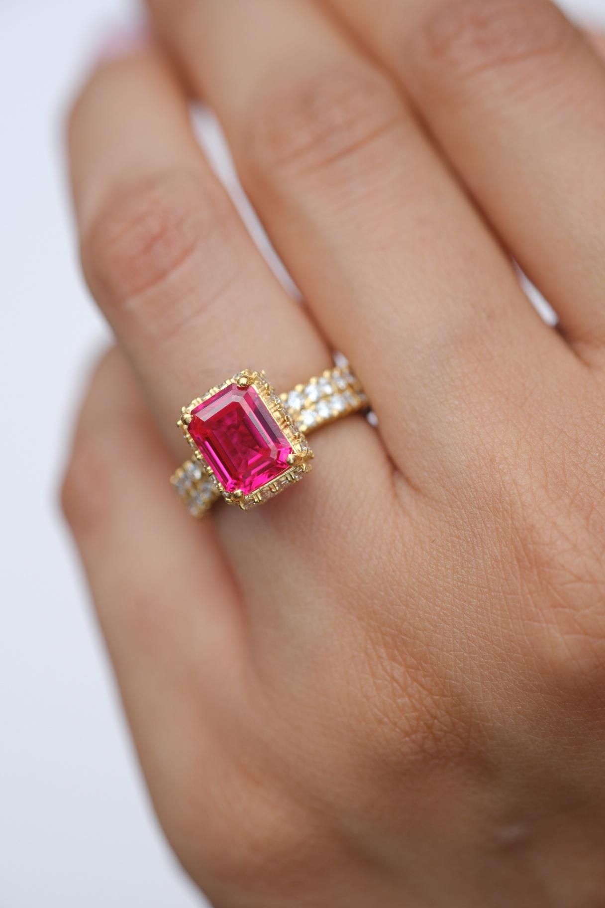 Emerald-cut pink sapphire, yellow gold halo